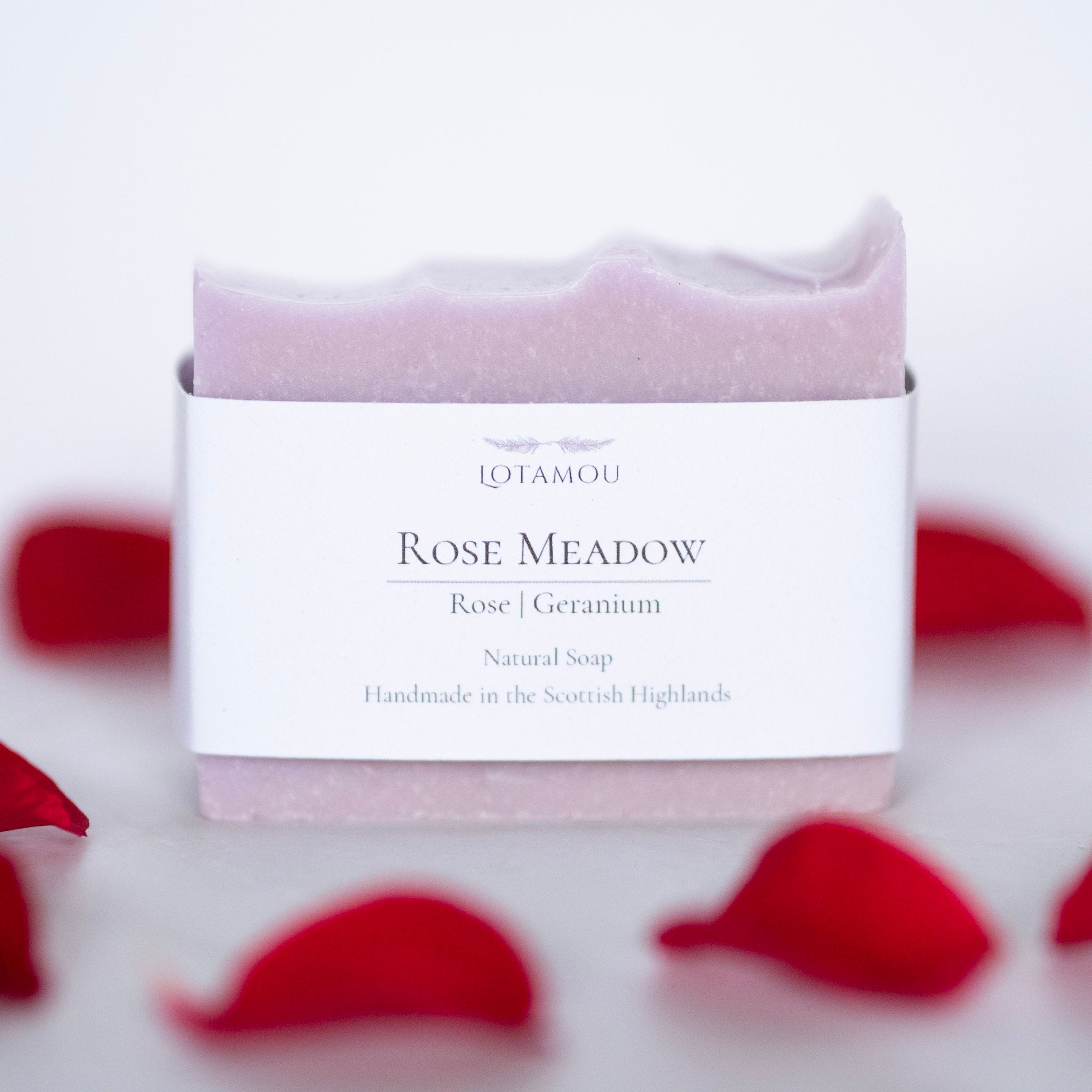 Rose Meadow soap bar with packaging on a white background with red rose petals.