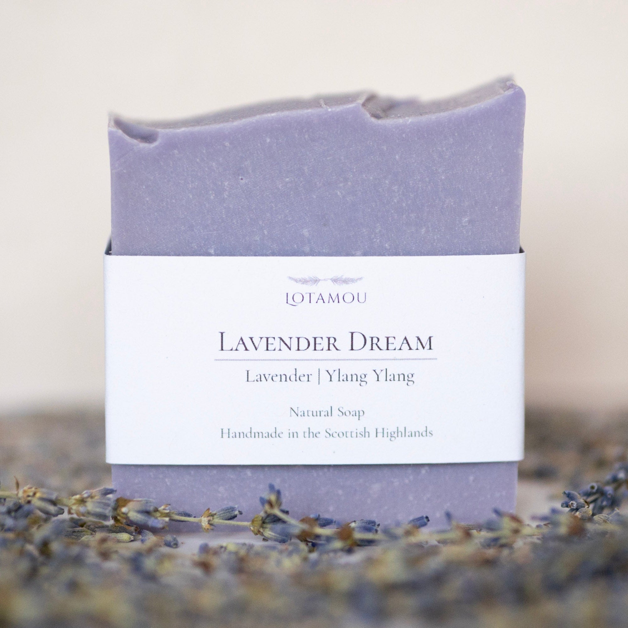 Lavender soap bar with packaging labeled 'Lavender Dream' on a blurred background with lavender flowers.