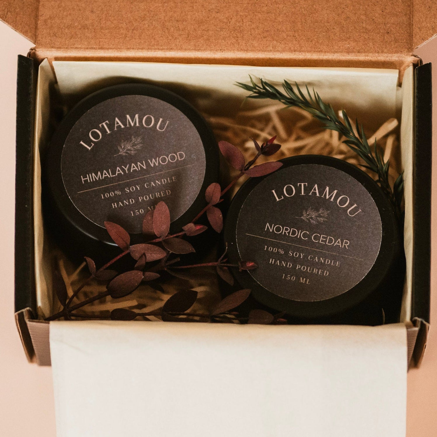 Two Lotamou candles in a box with decorative elements