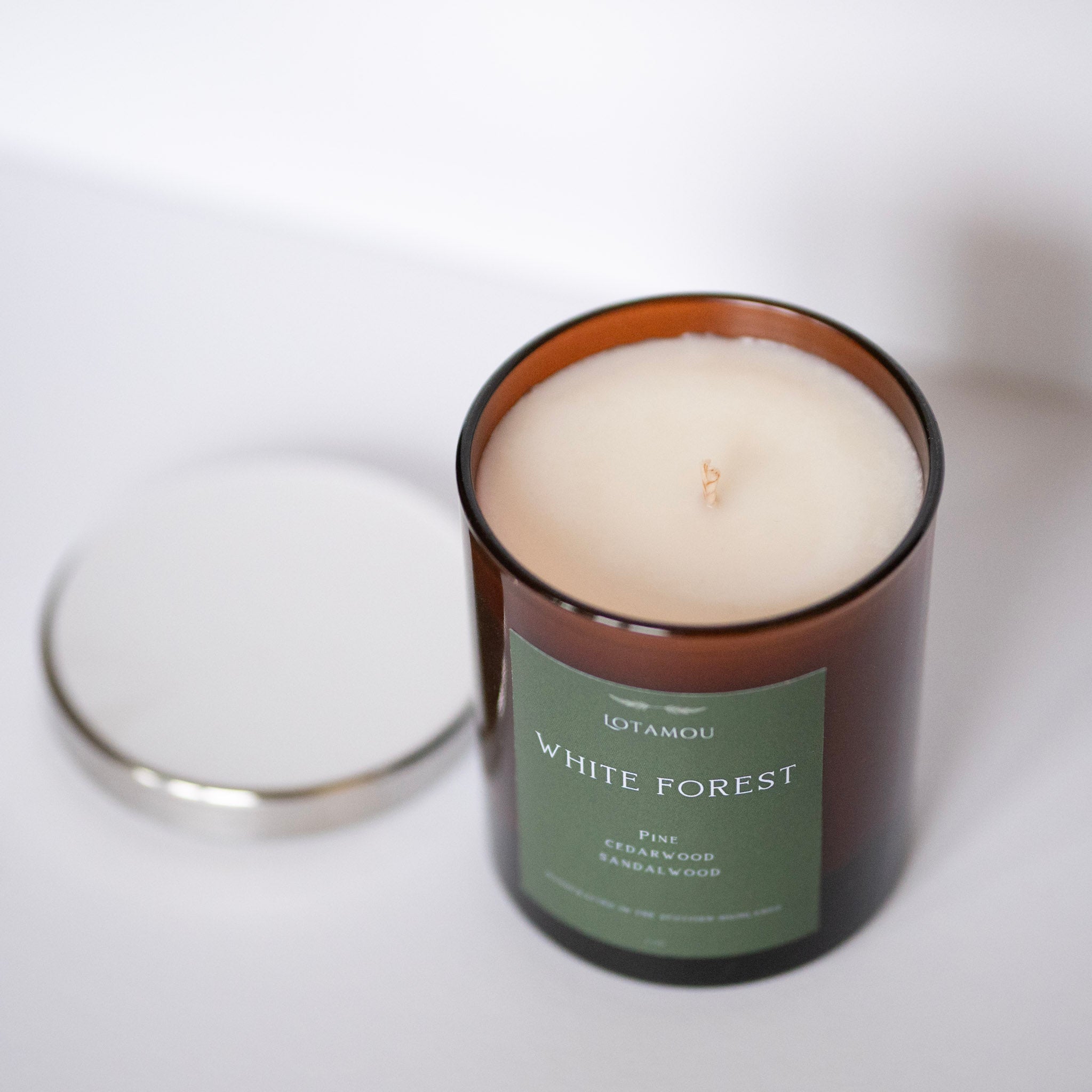 Candle in a brown container with a green label on a white background