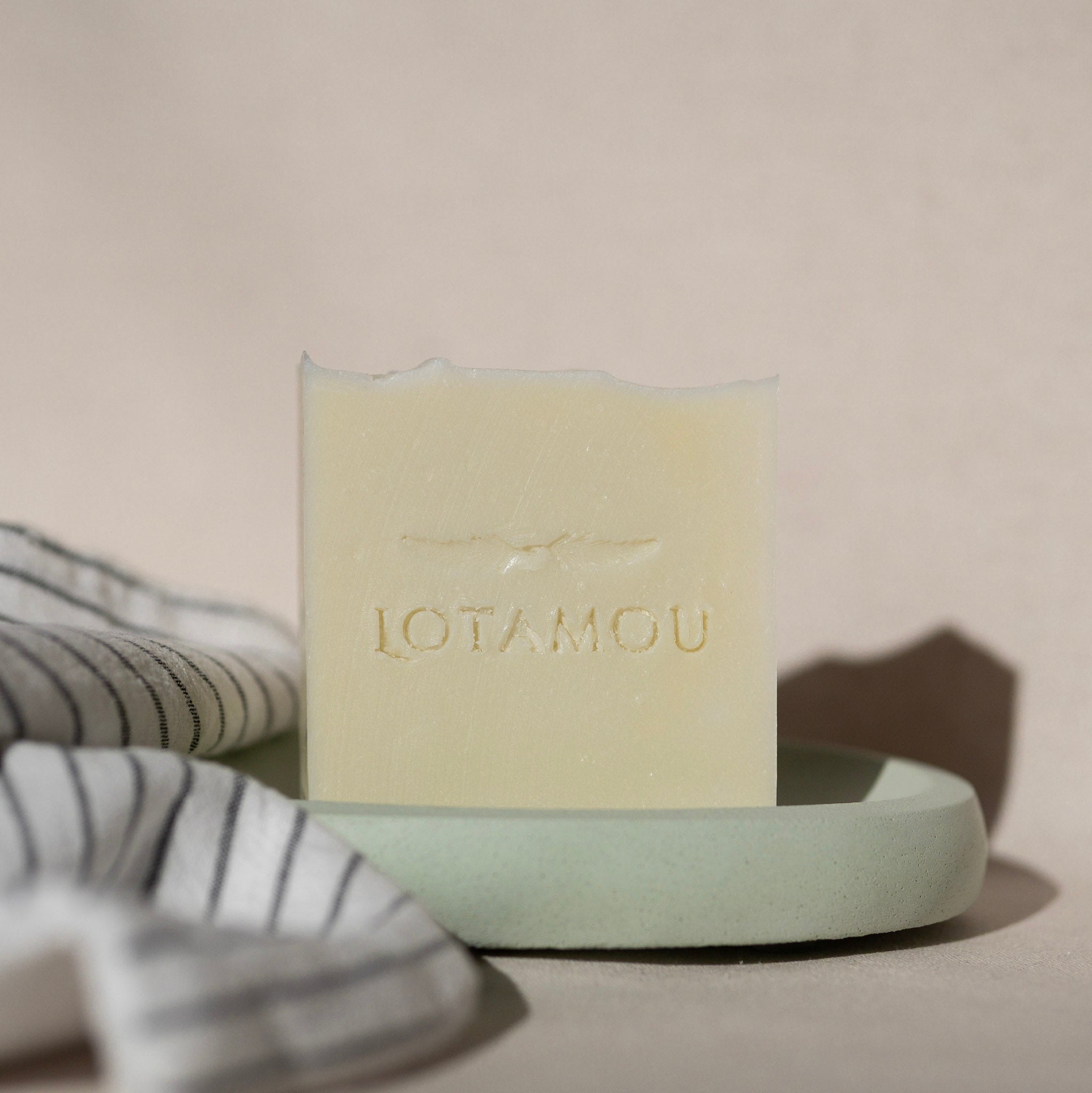 Light green soap bar with 'LOTAMOU' branding on a white background