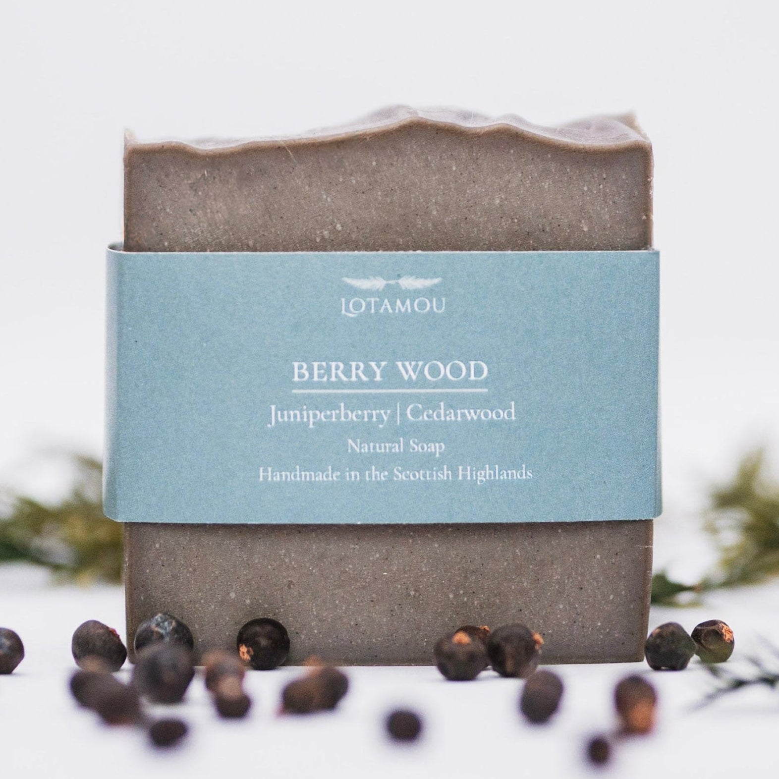 Bar of soap with a blue label on a white background with berries and greenery.