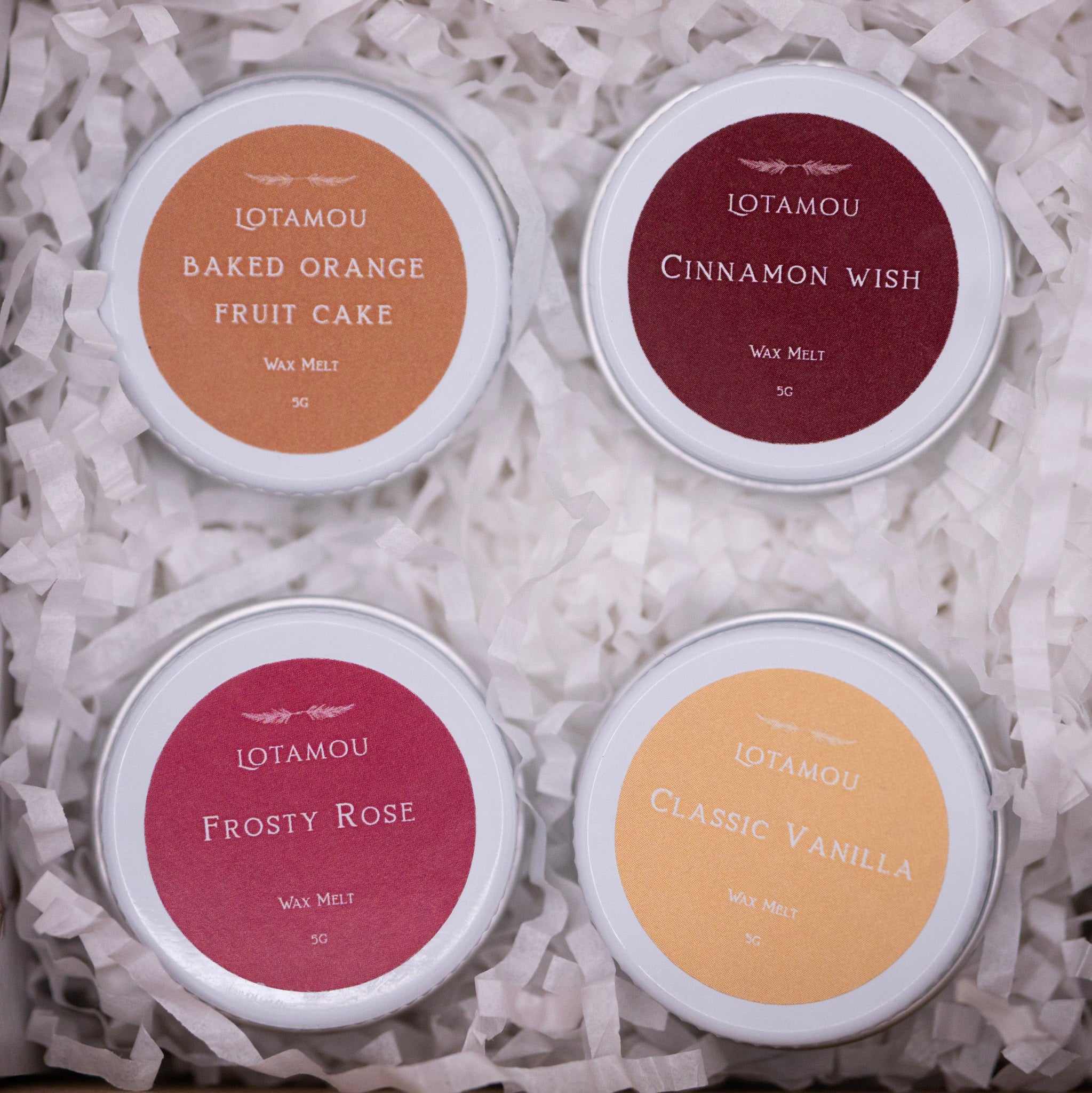 Four Lotamou wax melt tins with different scents on a white background