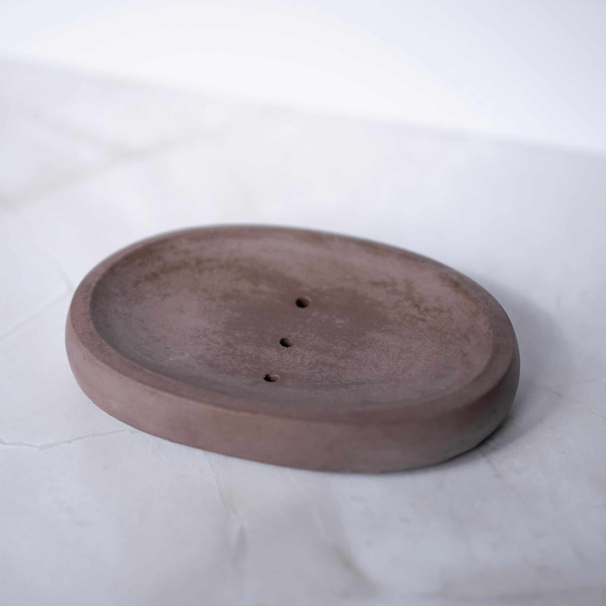 Round concrete soap dish with two holes on a white background