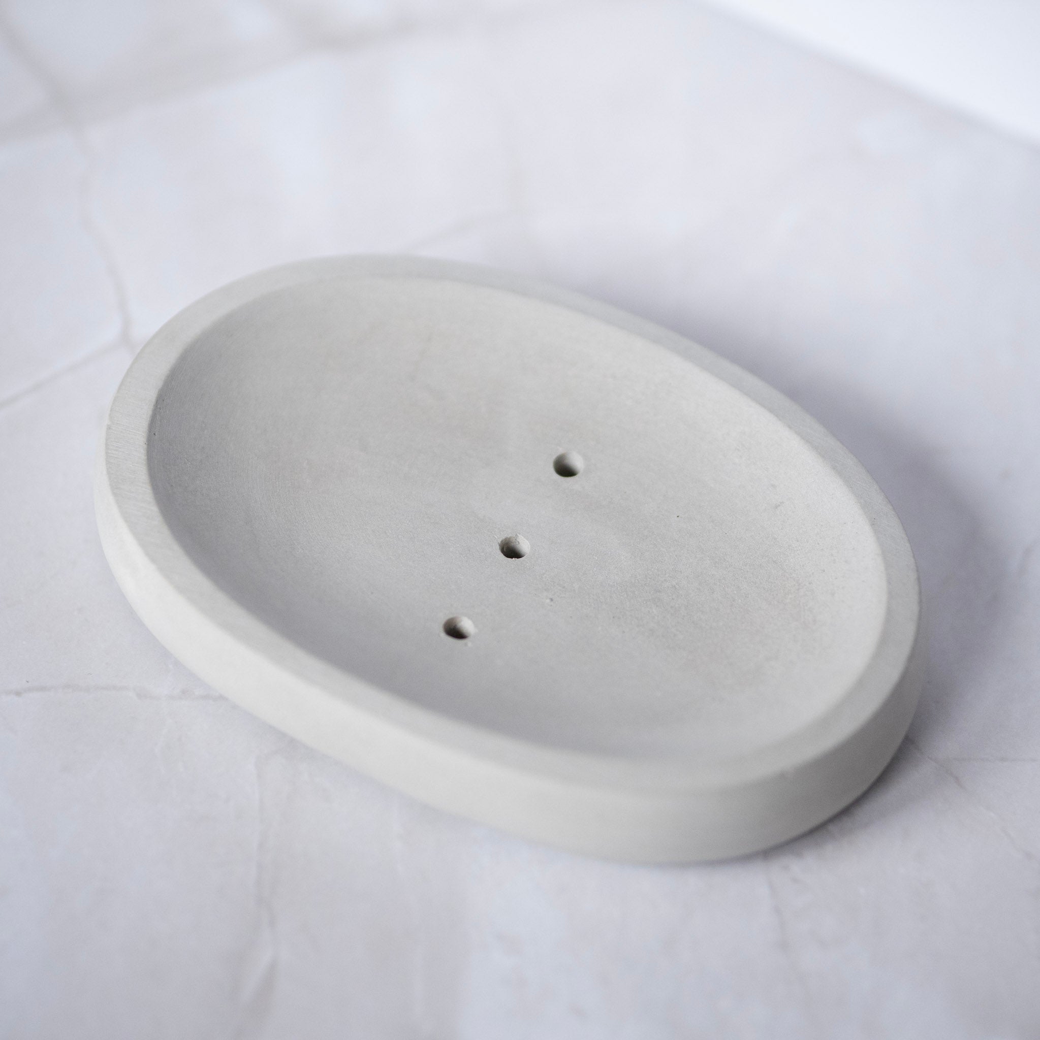 Concrete soap dish with three holes on a white background