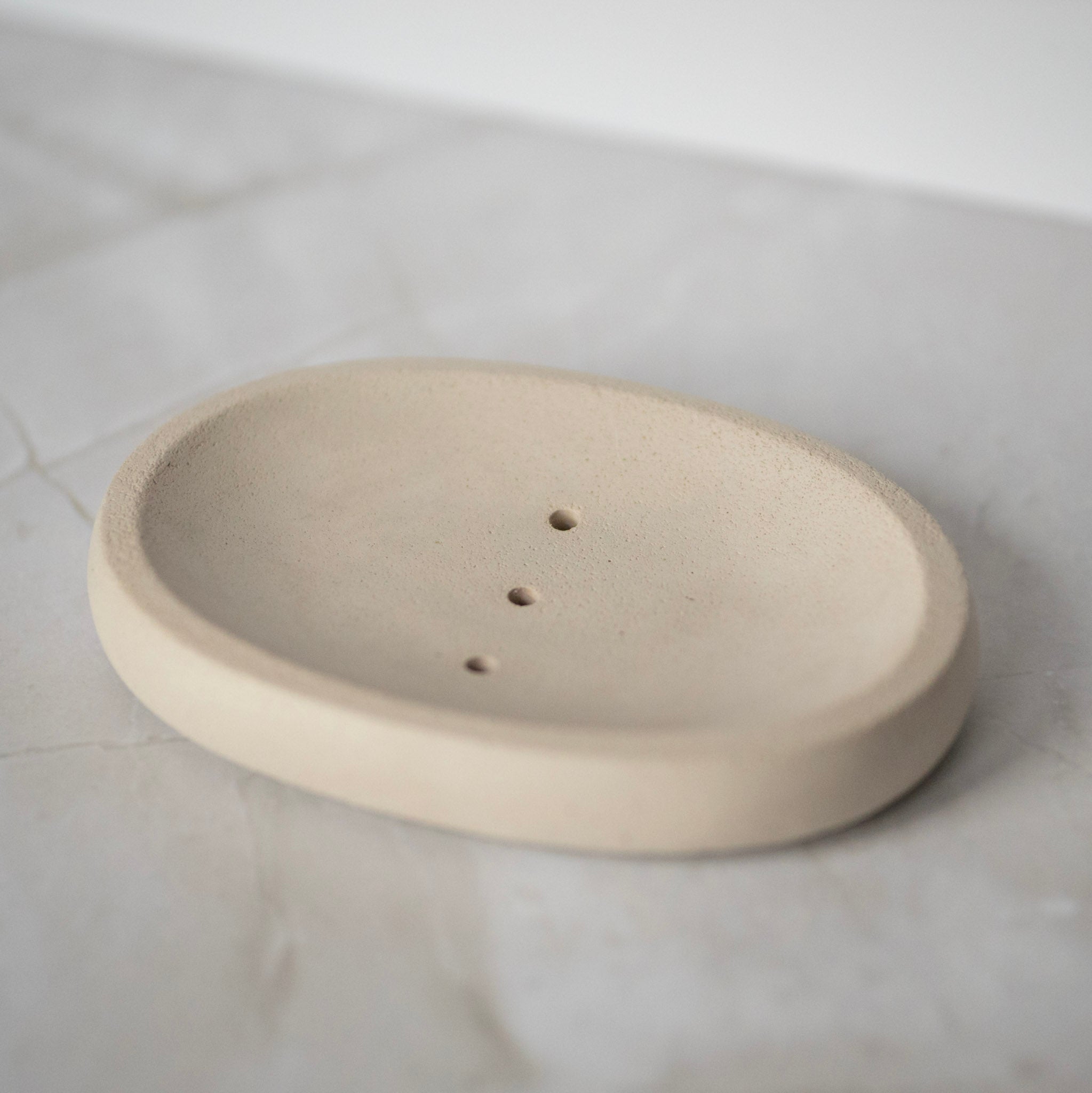Beige ceramic soap dish on a white marble surface